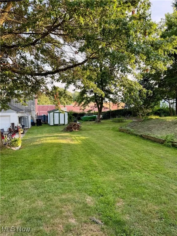 View of green lawn with a storage unit and a garage