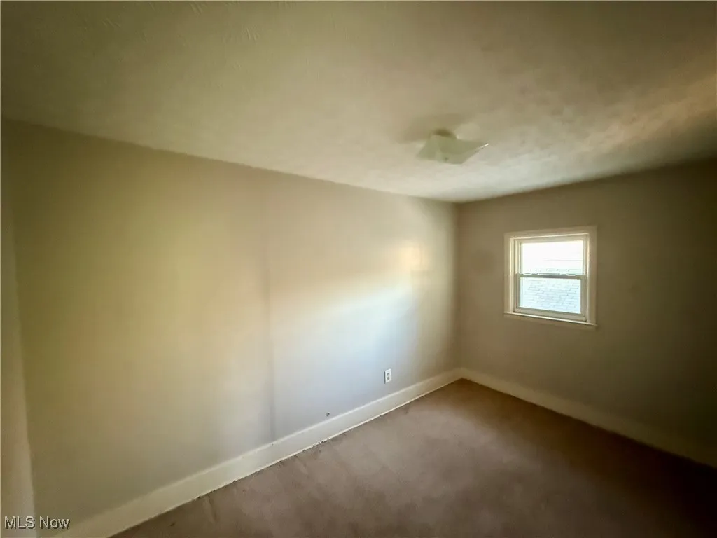 Spare room featuring baseboards and carpet