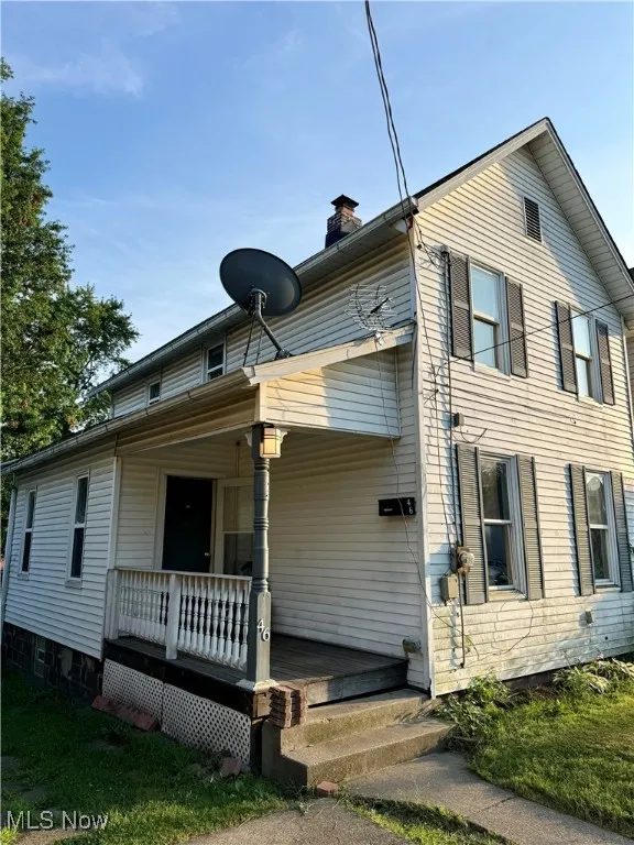View of front facade with a porch and a chimney