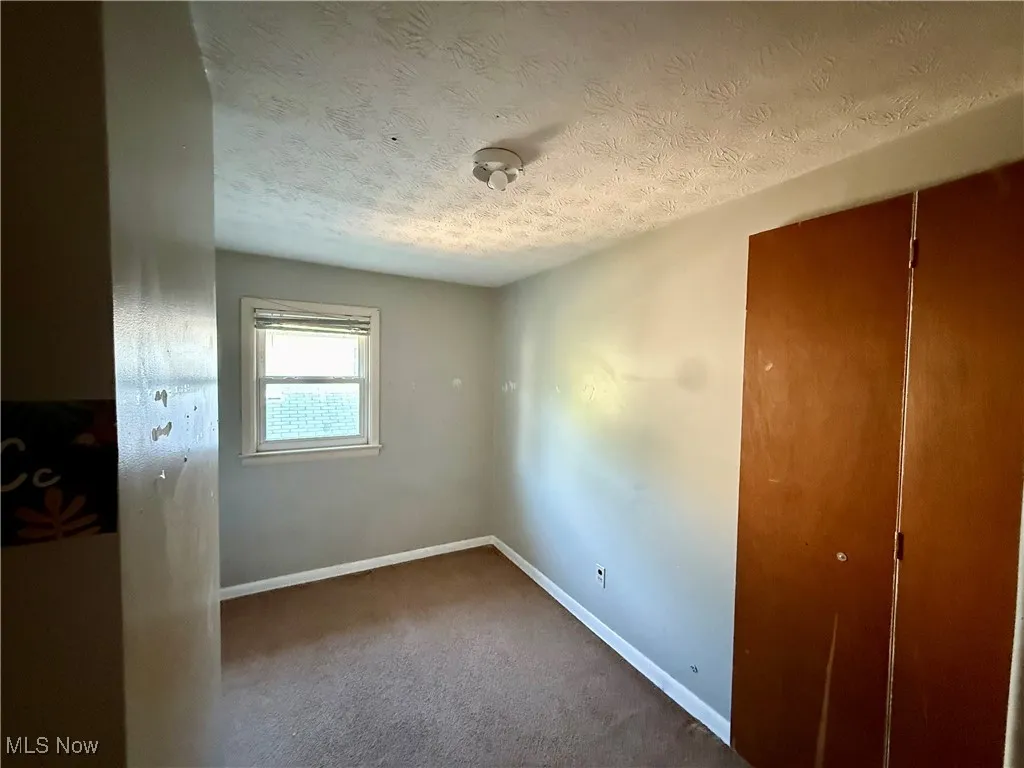 Unfurnished bedroom with a textured ceiling, carpet, and a closet