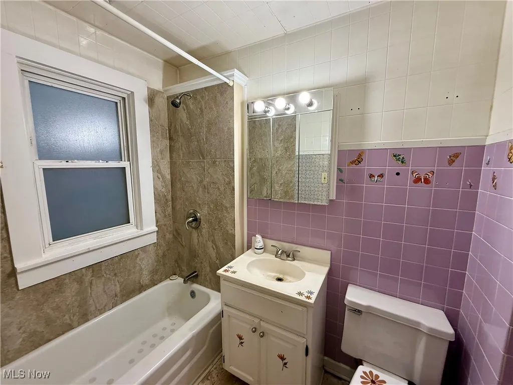 Full bath featuring tile walls, vanity, and shower / bath combination