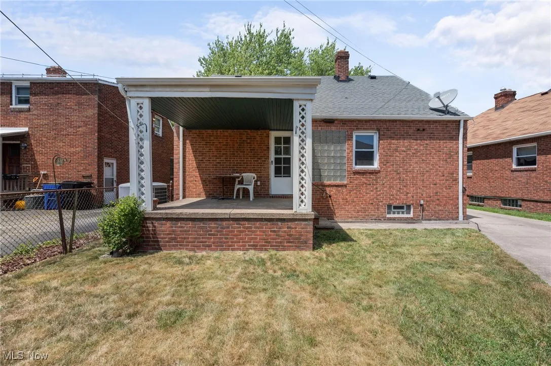 Back of house with brick siding, a chimney, and a porch