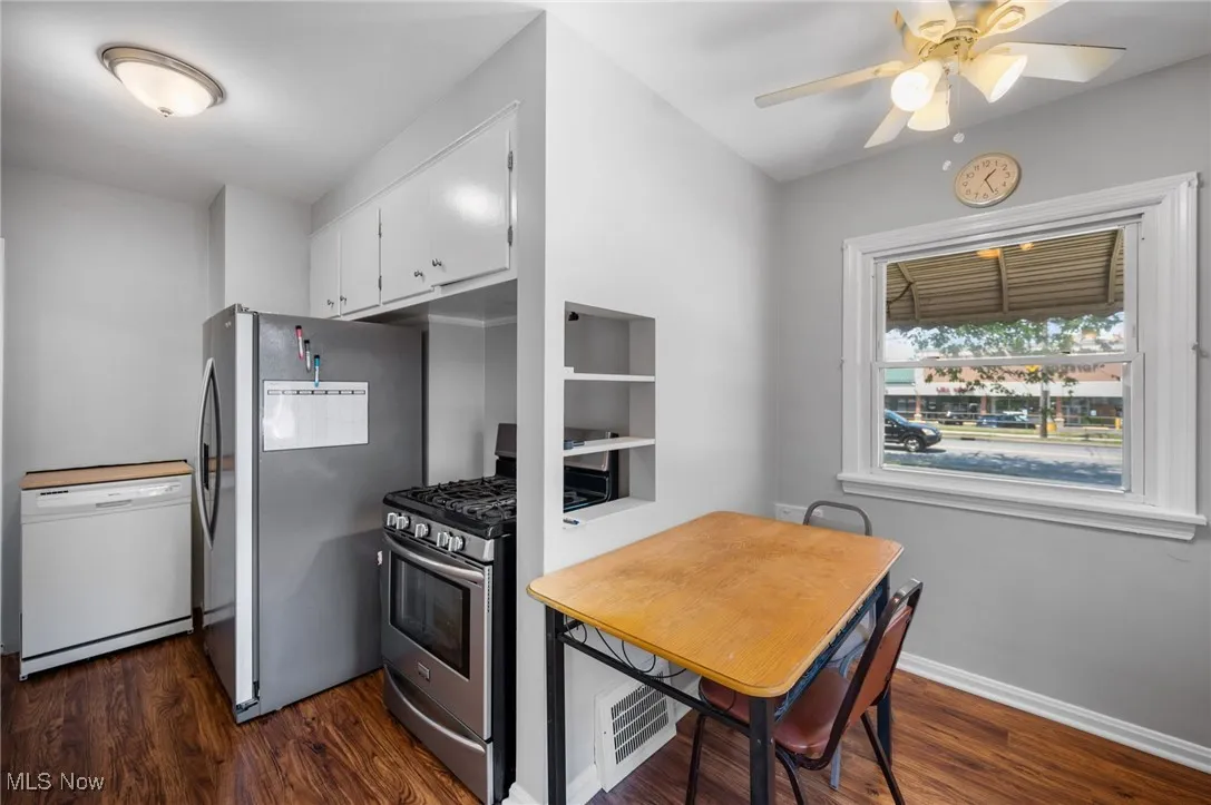Kitchen featuring stainless steel appliances, dark wood-style floors, a ceiling fan, and white cabinetry