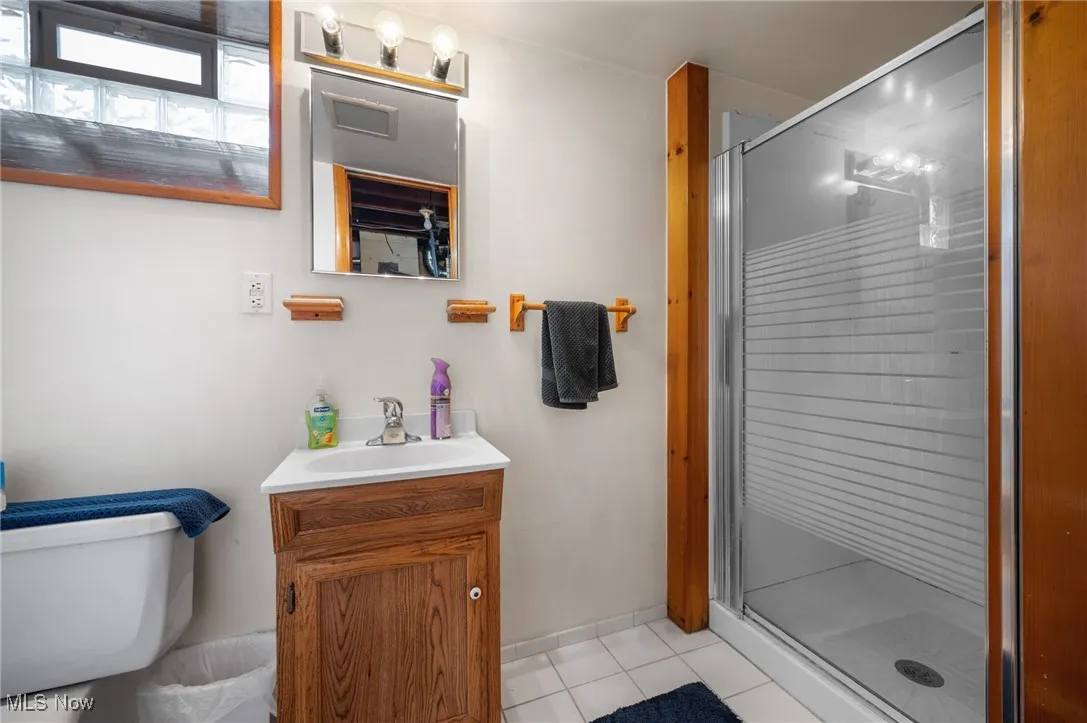 Bathroom with tile patterned flooring, vanity, and a shower stall