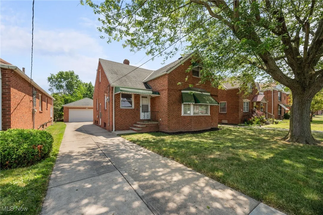 Bungalow-style house with brick siding, a front lawn, a garage, and roof with shingles