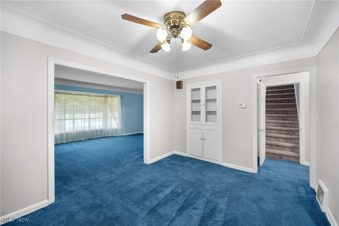 dining room with carpet floors, ceiling fan, and stairway