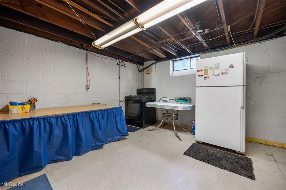 Basement with freestanding refrigerator and light flooring