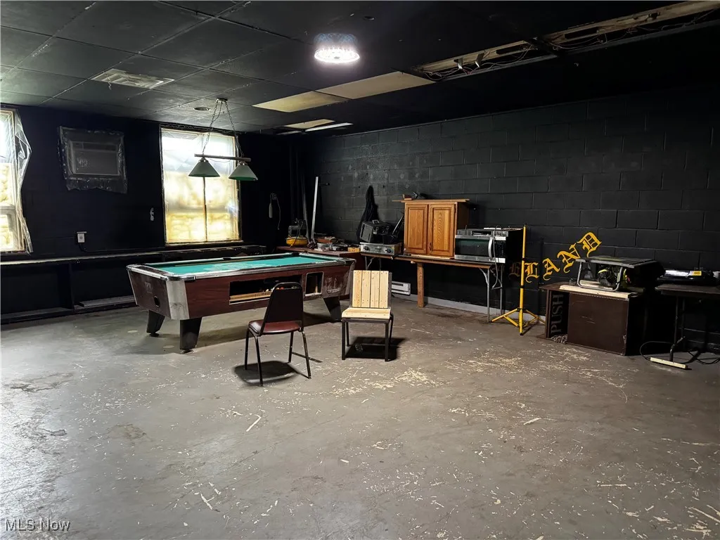 Recreation room with concrete flooring, billiards, and concrete block wall