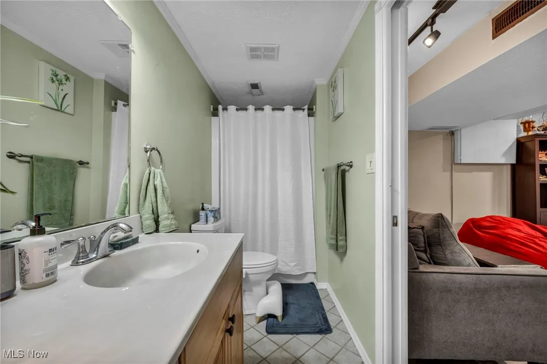 Full bath featuring vanity, curtained shower, and tile patterned floors