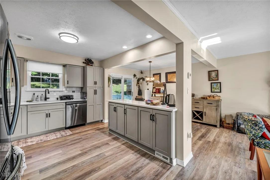 Kitchen featuring gray cabinetry, light wood-style floors, black refrigerator, light countertops, and a textured ceiling