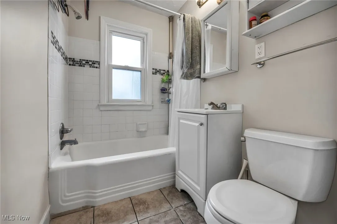 Bathroom featuring shower / tub combo, vanity, and tile patterned flooring