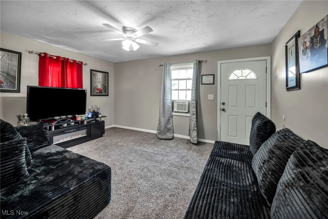 Carpeted living room with a ceiling fan and cooling unit