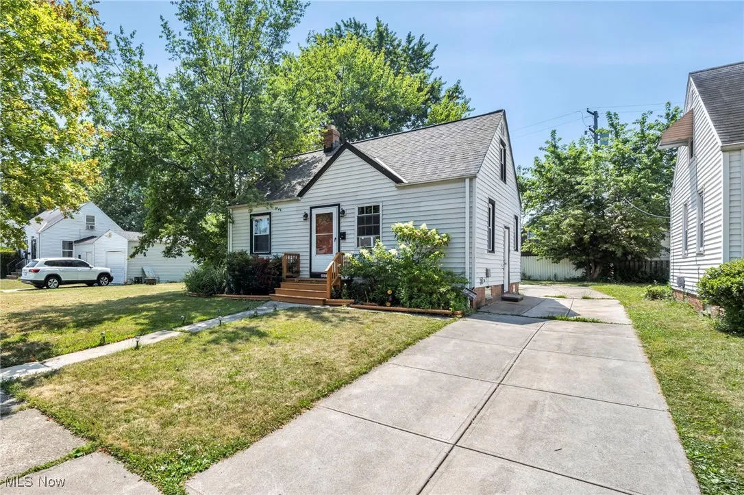 Bungalow-style house with roof with shingles, a chimney, a front yard, and concrete driveway