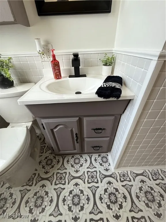 Bathroom featuring tile walls, vanity, tile patterned flooring, and wainscoting