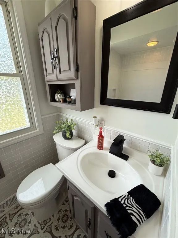 Bathroom with vanity, tile walls, tile patterned flooring, and a wainscoted wall