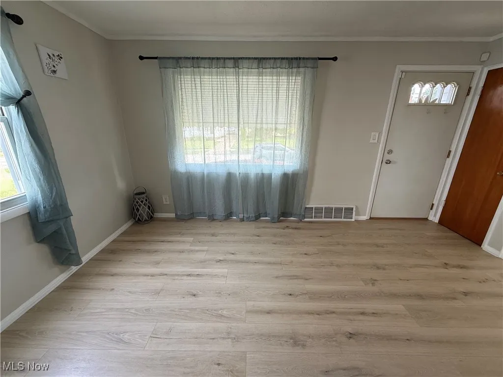 Foyer featuring crown molding and wood finished floors