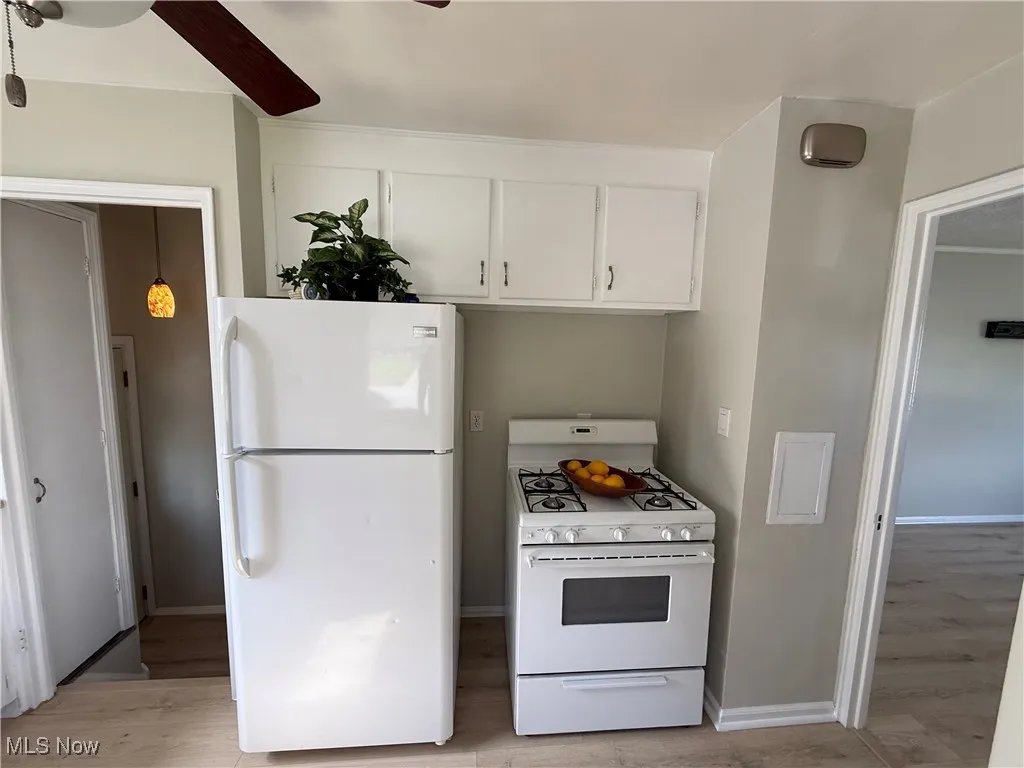 Kitchen featuring white appliances, white cabinetry, light wood-style flooring, and a ceiling fan