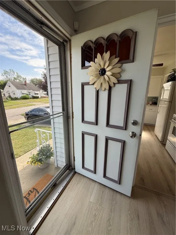 Foyer with light wood-style floors and crown molding
