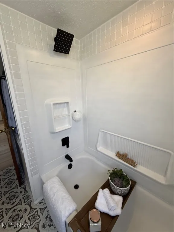 Full bathroom featuring a textured ceiling and washtub / shower combination