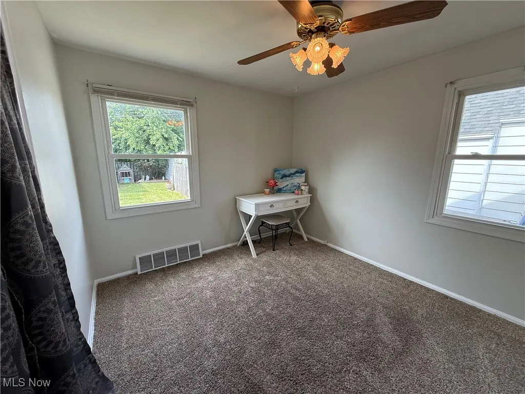 Carpeted empty room featuring healthy amount of natural light and a ceiling fan