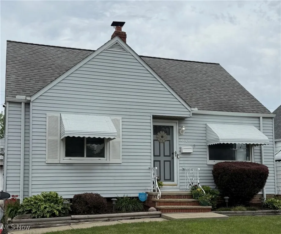 Bungalow-style house with a shingled roof, a chimney, and entry steps