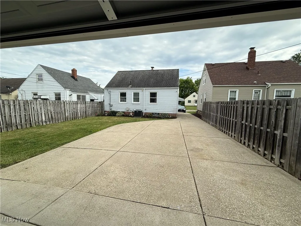 Back of property featuring driveway, a patio, a fenced backyard, and a residential view