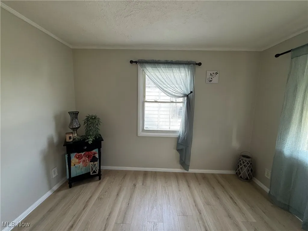 Unfurnished room with wood finished floors, crown molding, and a textured ceiling