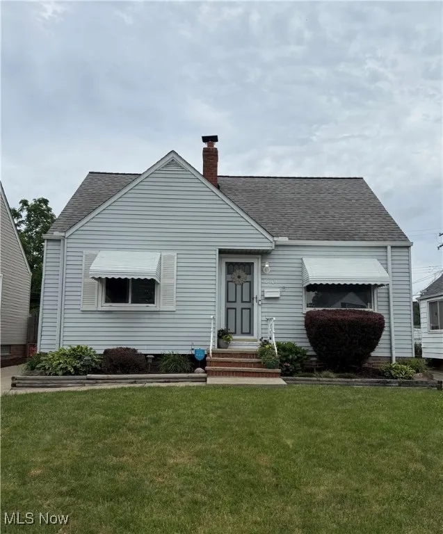 View of front of home with roof with shingles, a chimney, a front lawn, and entry steps