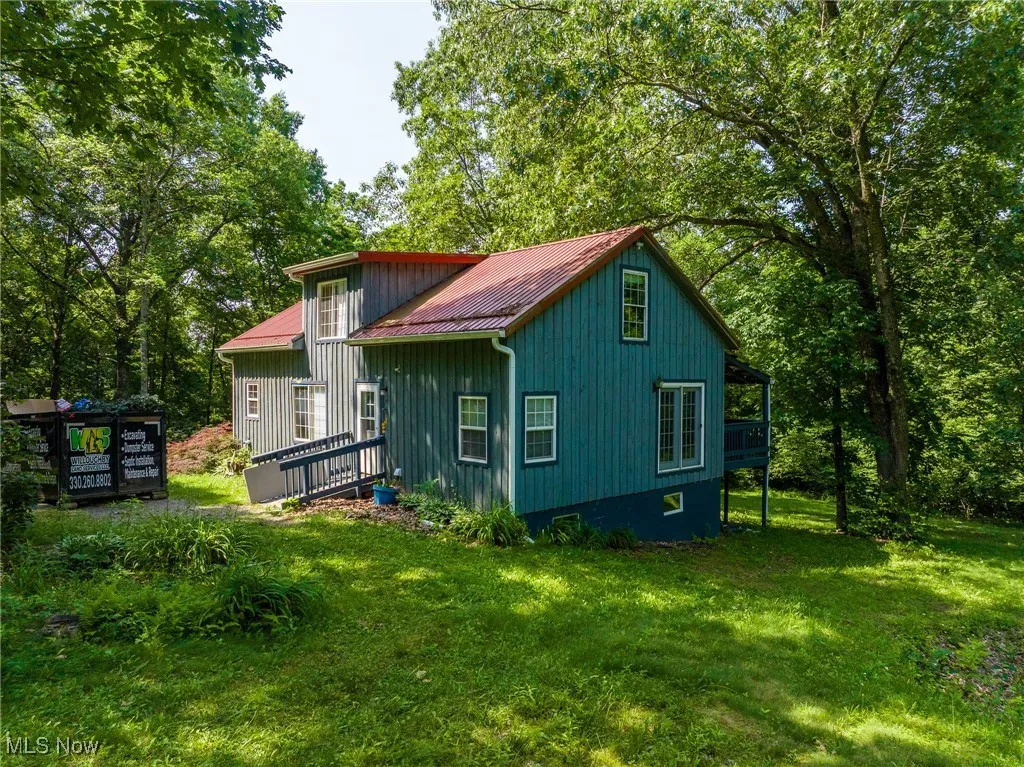 Rear view of property featuring a lawn, a metal roof, and a wooden deck