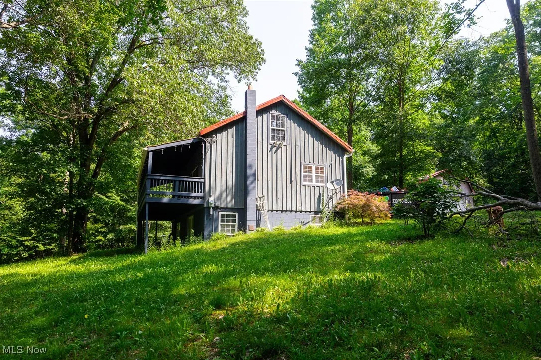 View of side of home with a chimney, board and batten siding, and a deck