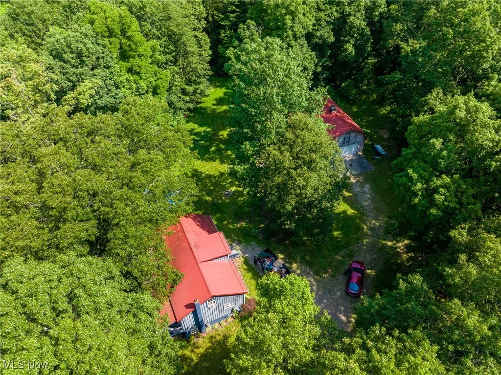 Aerial view of property and surrounding area with a forest