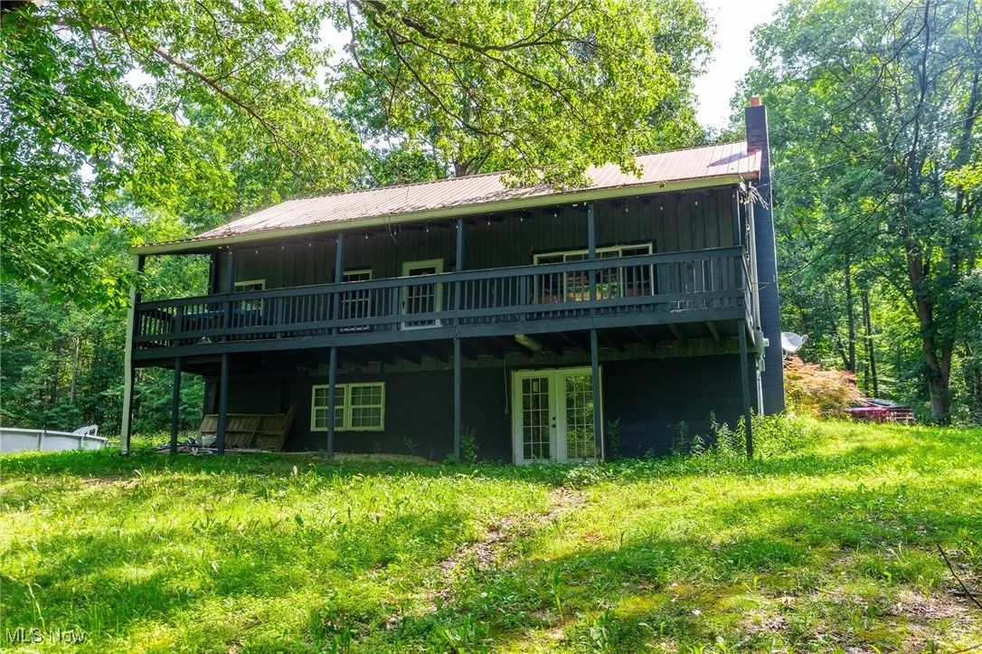 Rear view of house featuring french doors, a deck, a chimney, and a metal roof