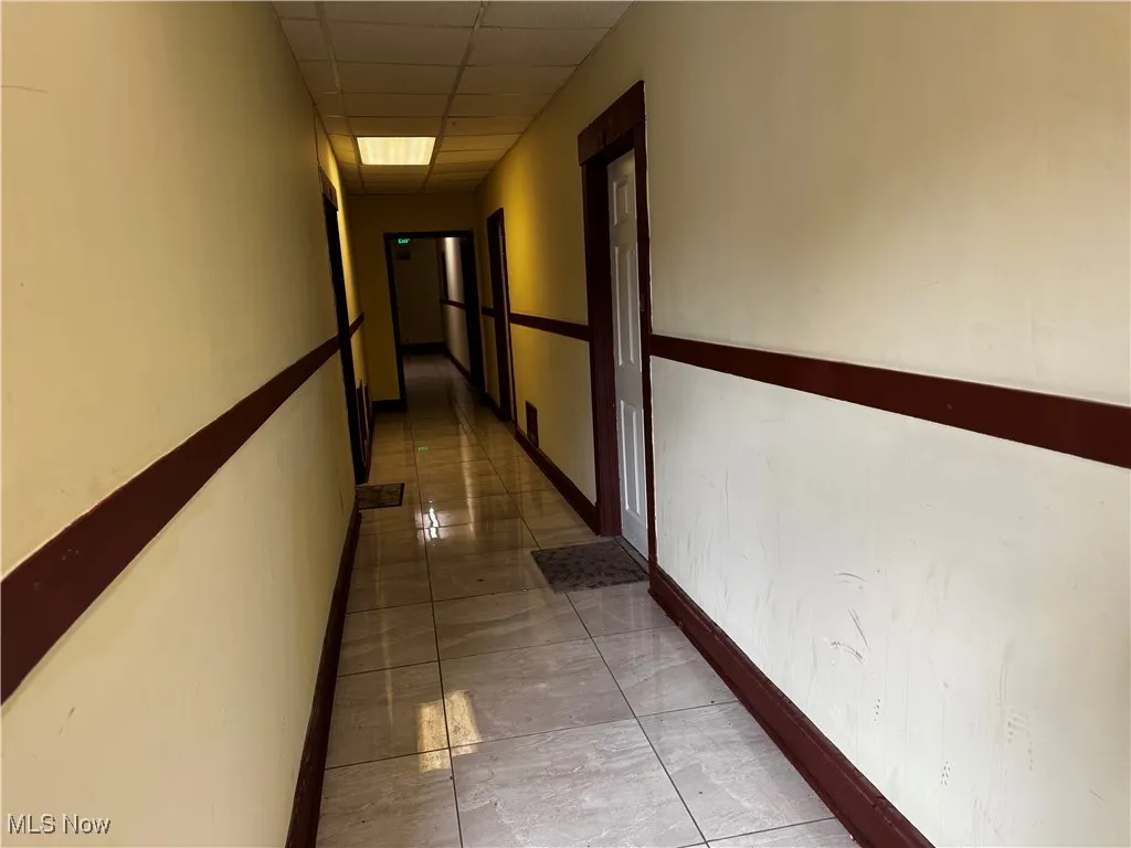 Hallway featuring a drop ceiling and baseboards