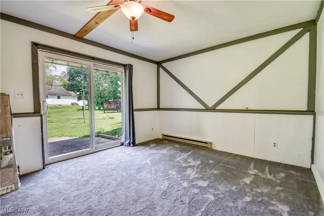 Spare room with carpet, a baseboard heating unit, and a ceiling fan