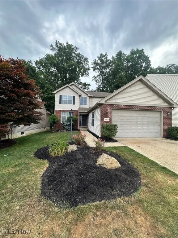 Traditional-style home with brick siding, driveway, a front lawn, and an attached garage