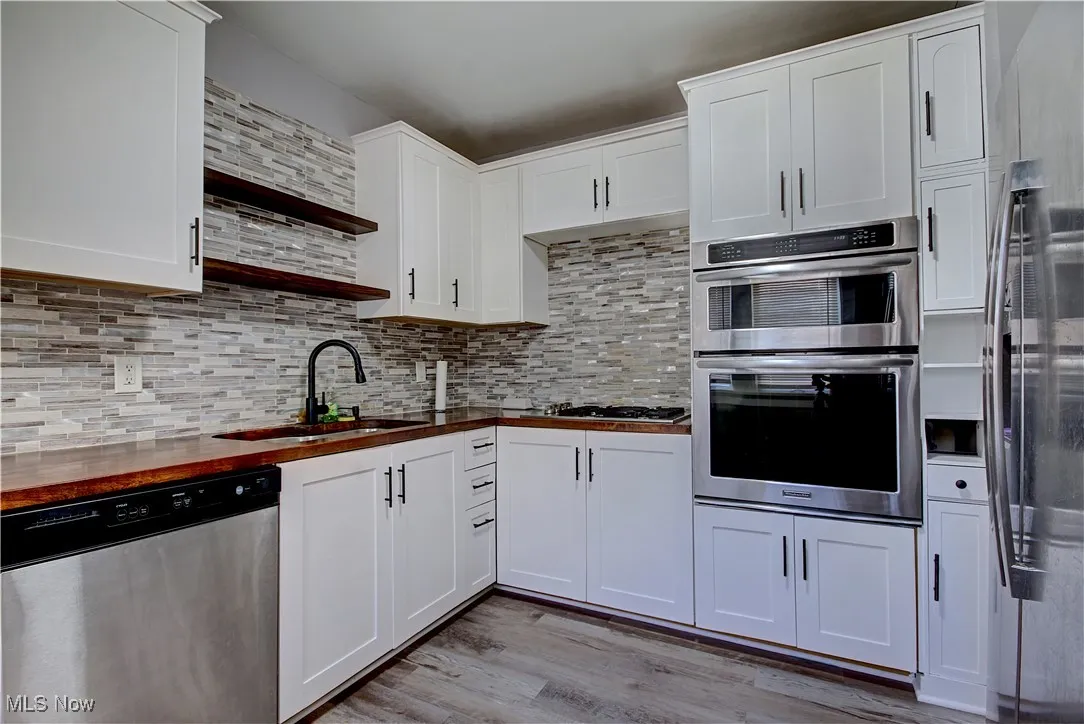 Kitchen featuring stainless steel appliances, light wood-style floors, white cabinets, and butcher block counters