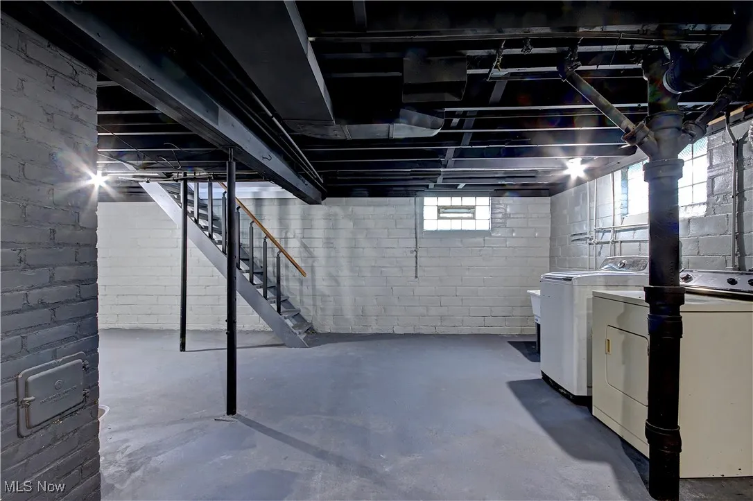 Basement with washing machine and clothes dryer and stairway