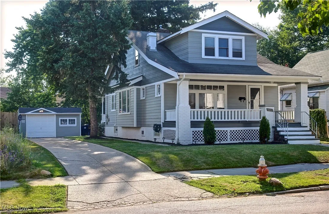 View of front facade with a porch, an outdoor structure, concrete driveway, a garage, and a front yard