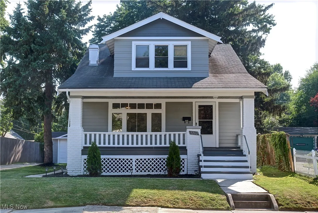 View of front facade with a porch, a shingled roof, and a chimney