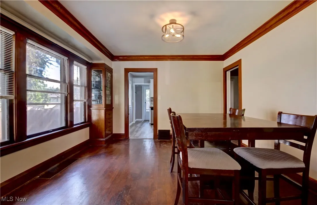 Dining space with dark wood-type flooring and ornamental molding
