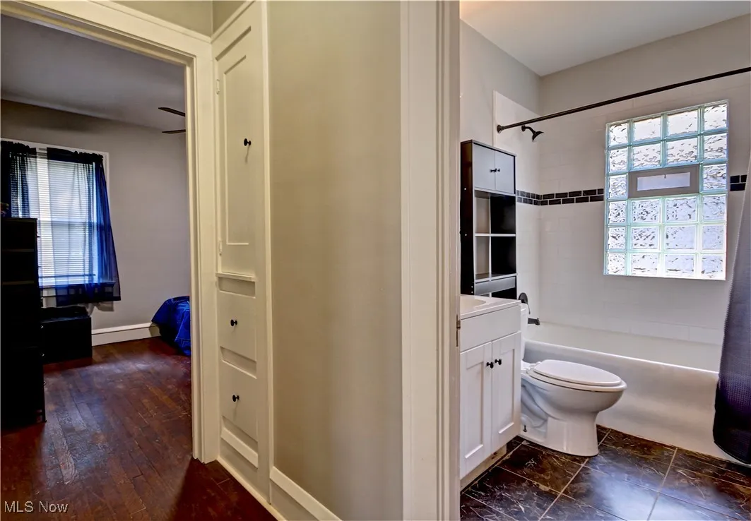 Bathroom with bathing tub / shower combination, vanity, and wood finished floors