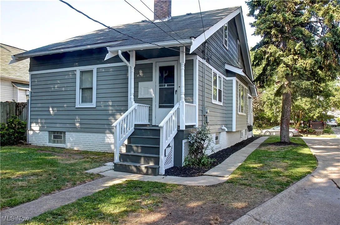 View of front facade featuring a chimney, a front yard, and a shingled roof