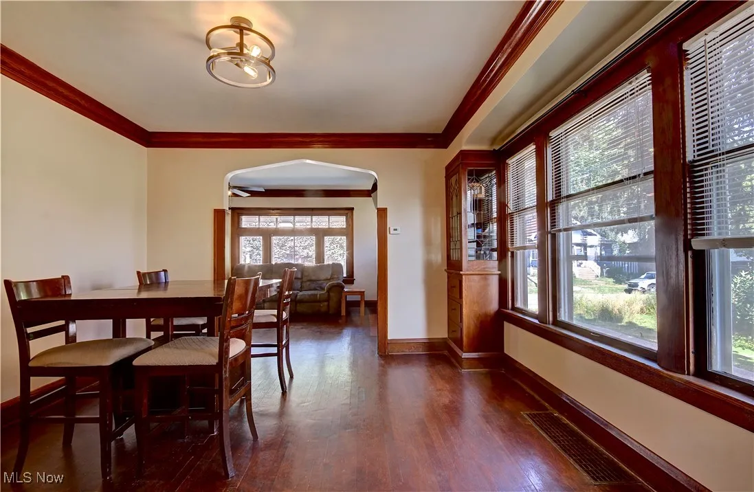Dining space featuring arched walkways, plenty of natural light, ornamental molding, and wood finished floors