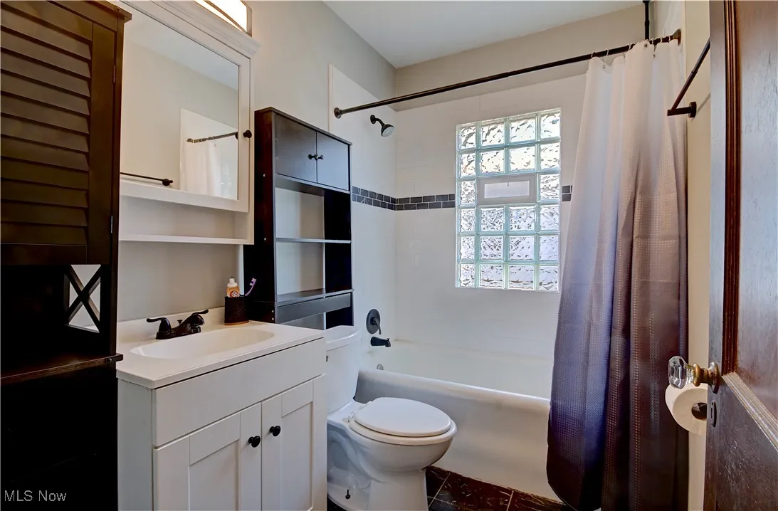 Full bath with shower / bath combo, vanity, and tile patterned floors