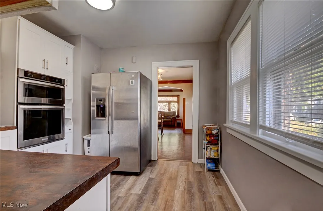 Kitchen with appliances with stainless steel finishes, light wood finished floors, and white cabinetry