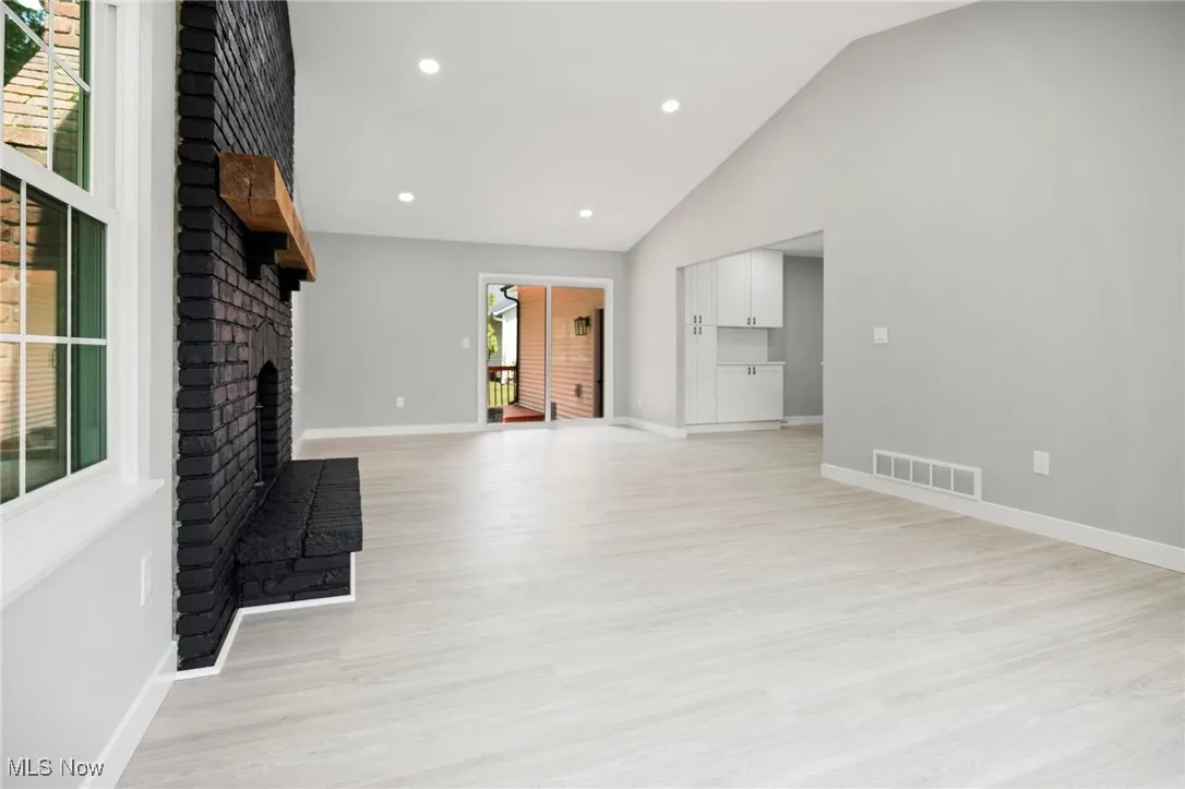 Unfurnished living room with a fireplace, light wood-style flooring, recessed lighting, and high vaulted ceiling