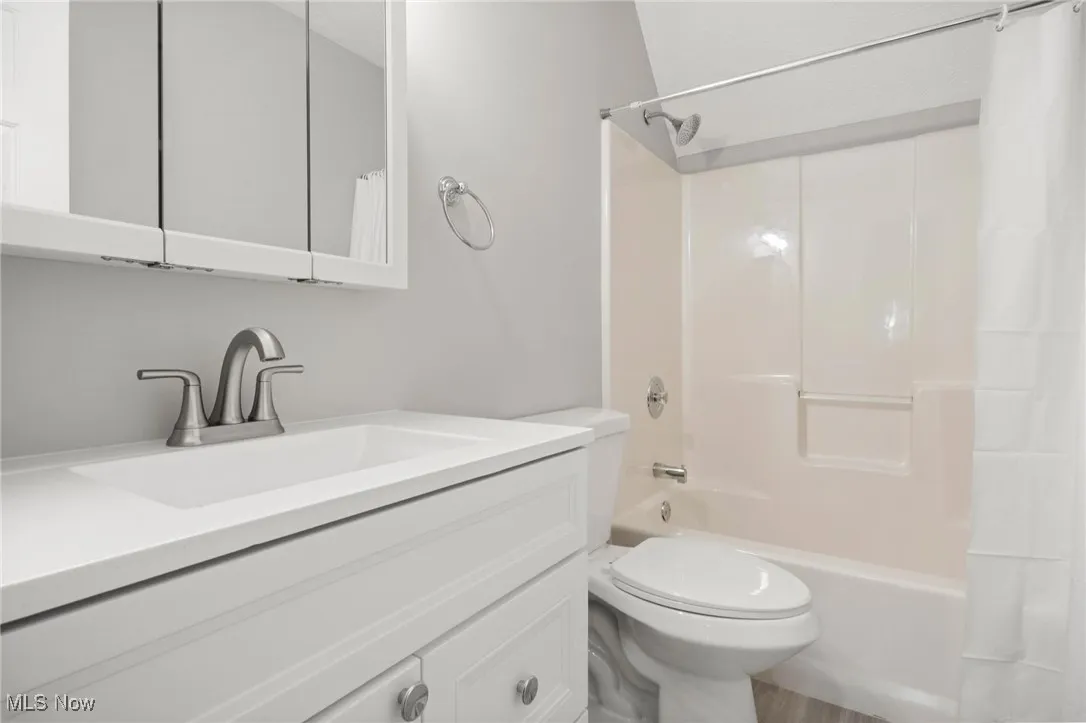 Bathroom featuring vanity and shower / bathtub combination with curtain