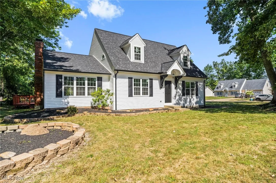 New england style home featuring a front yard, roof with shingles, and a chimney