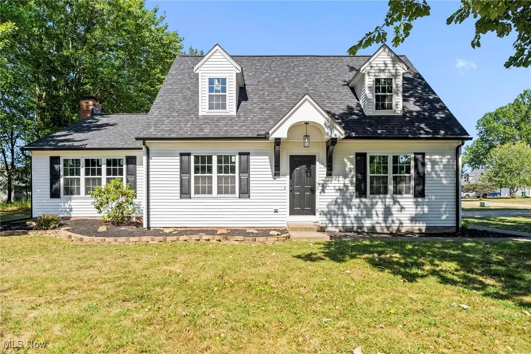 Cape cod house with a front lawn, roof with shingles, and a chimney