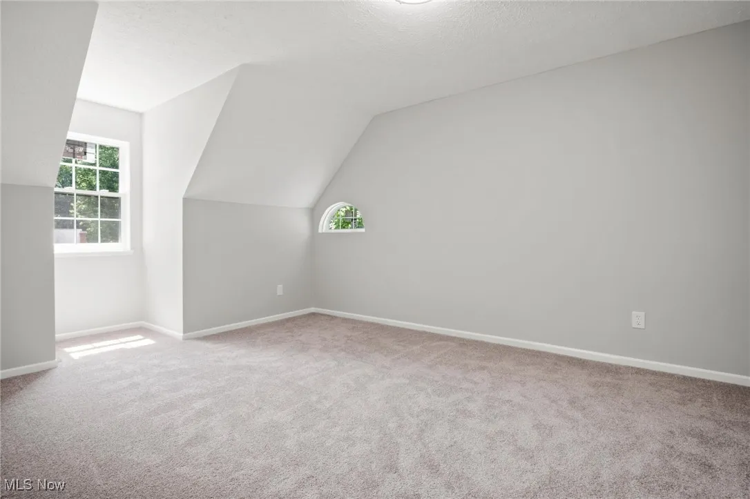 Additional living space with vaulted ceiling, carpet floors, and a textured ceiling